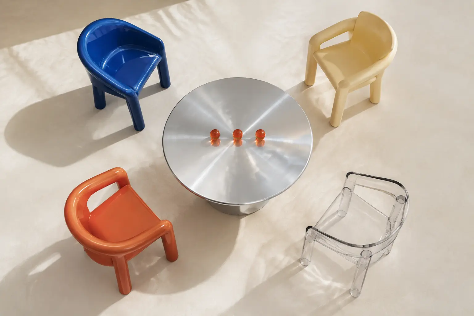 An overhead conversation table with four chairs, colorful cards, and three coral dots